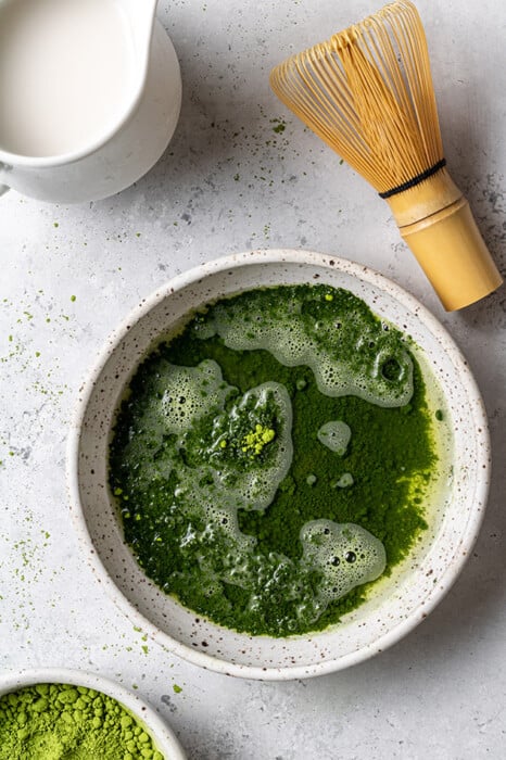 Whisked matcha powder in a white bowl