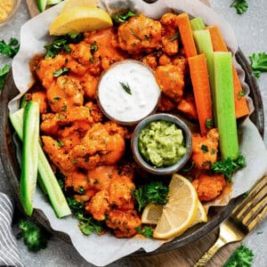 Top view of cauliflower wings in a grey plate with celery and carrots