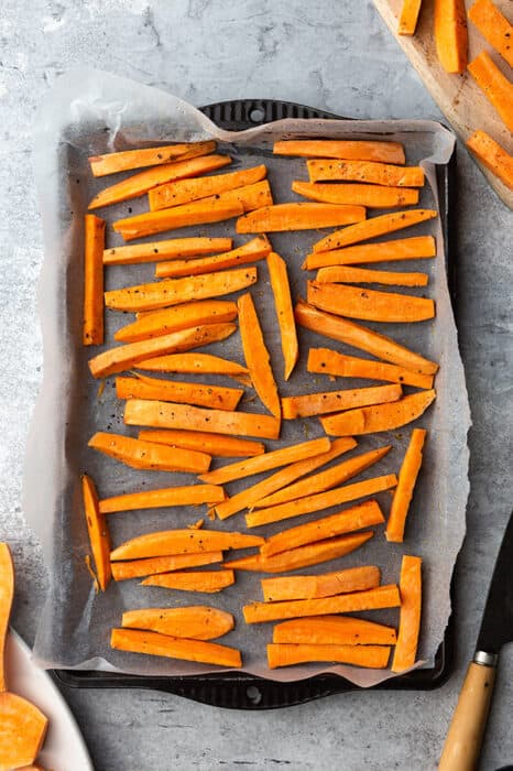 Top view of sliced sweet potatoes on a baking sheet