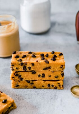 Close up side view of three stacked homemade protein bars on a grey background