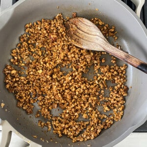 The cauliflower walnut filling in a saucepan with a wooden spoon stirring it around