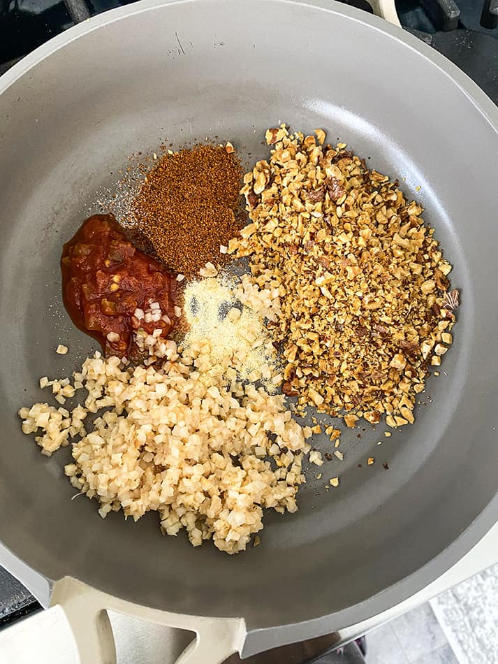 Finely chopped walnuts, cauliflower rice, taco seasoning, salsa and garlic powder in a metal saucepan