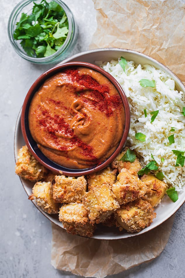 A bowl with tofu nuggets and spicy peanut dip