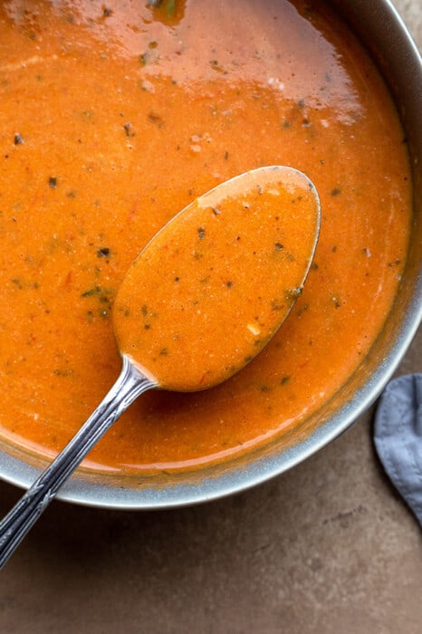 Close-up view of vegan tomato soup in a pot with a spoon