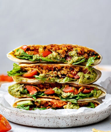 Side view of four vegetarian crunchwrap halves stacked on a white plate