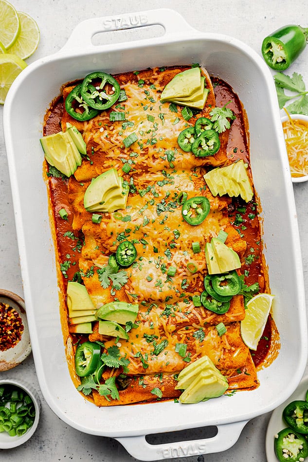 Overhead view of a pan of vegetarian enchiladas topped with Mexican garnishes