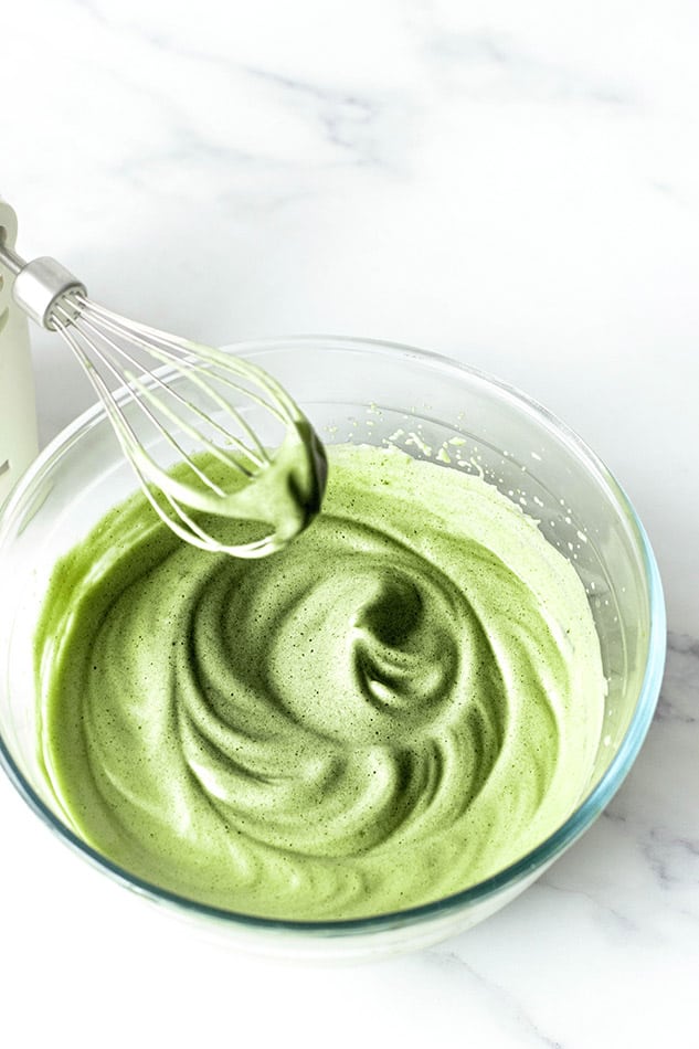 Image of glass bowl filled with whipped matcha with whisk.