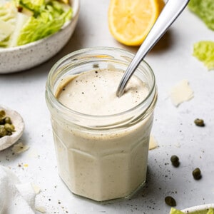 45 degree shot of Vegan Caesar Dressing in a small jar with a spoon