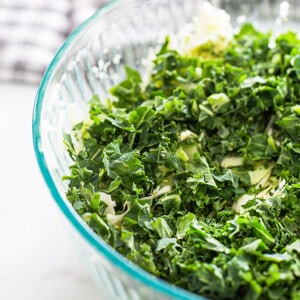Chopped kale, green onions, cucumber and cabbage in a large clear mixing bowl