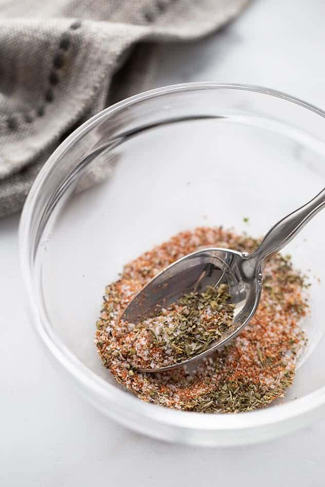 Mixed fajita seasonings in a clear bowl with a spoon