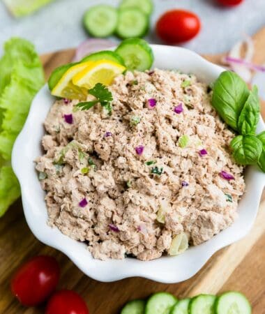 Top view of low carb paleo tuna salad in a white bowl on a wooden board