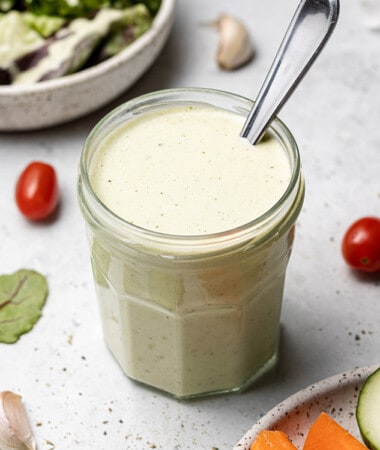 45 degree shot of ranch salad dressing in a small jar with a spoon