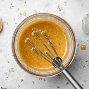 Top view of blended asian sesame ginger dressing in a glass jar with a whisk