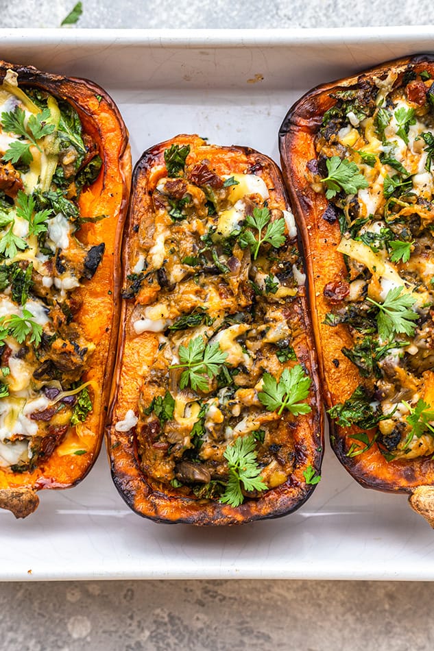 Overhead view of three stuffed butternut squash halves in a baking dish