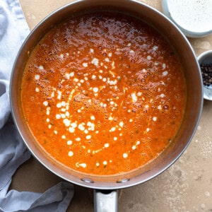 Top view of a pot of healthy tomato soup on a beige background