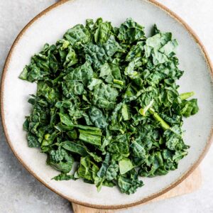 Top view of chopped kale in a white bowl on a grey background