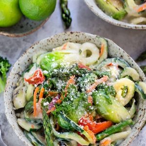 Overhead view of Zoodles Cauliflower Alfredo in a bowl with spring vegetables