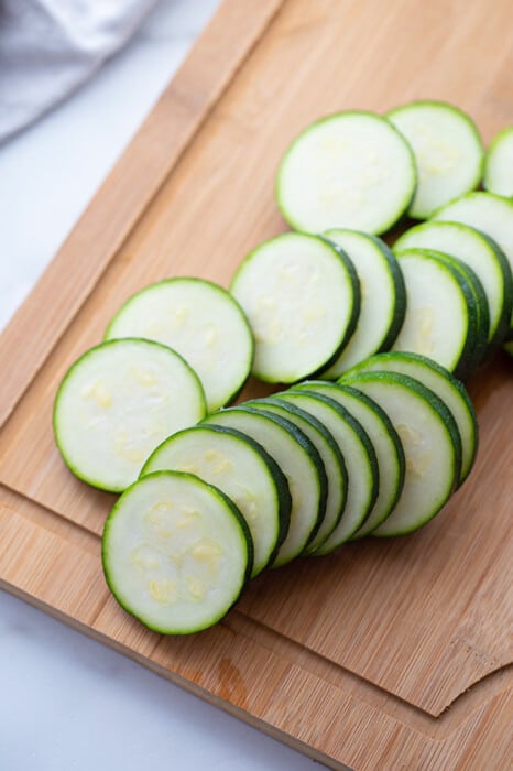 Sliced zucchini rounds on a wooden cutting board