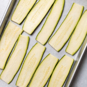 10 strips of fresh zucchini ribbons on a parchment lined baking sheet