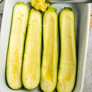 Top view of raw hollowed-out zucchini in a white casserole dish