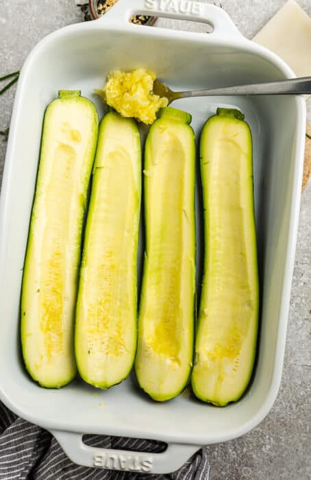 Top view of raw hollowed-out zucchini in a white casserole dish