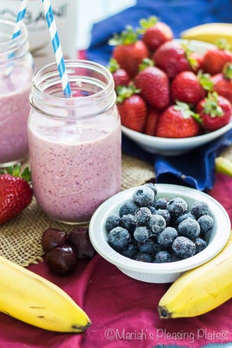 Berry Cherry Smoothie in a jar next to bowls of berries