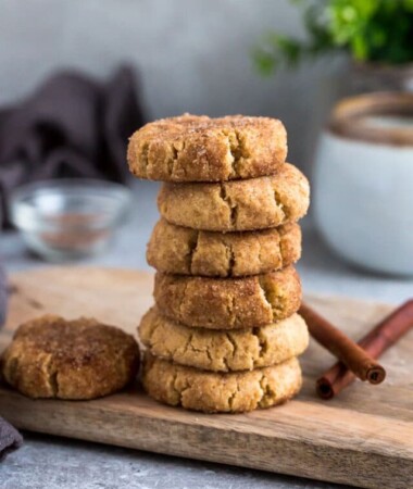 Side view of 6 stacked low carb paleo soft snickerdoodle cookies on a wire rack on a grey background