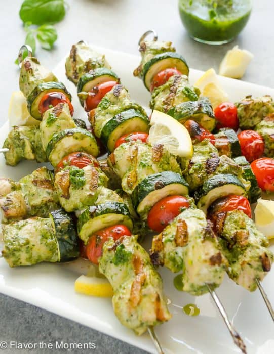 Grilled lemon pesto chicken kebabs stacked on a plate