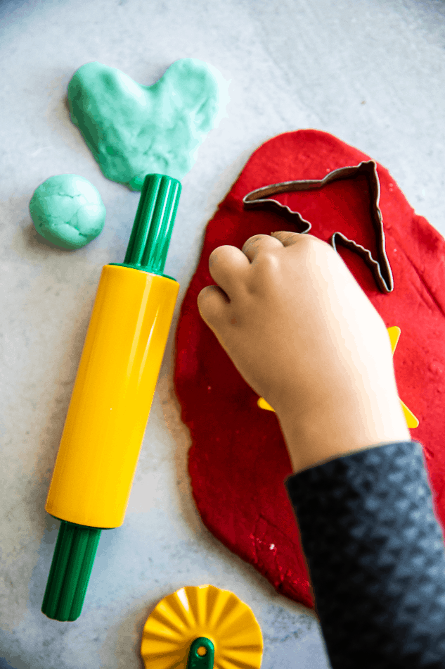 image of child's hand playing with homemade playdough with cookie cutters