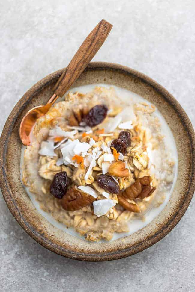 carrot cake oatmeal in brown bowl with raisins and coconut flakes