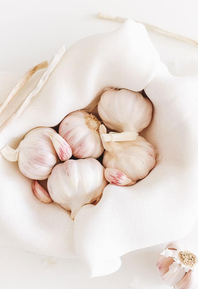 A bowl of garlic bulbs with a white linen.