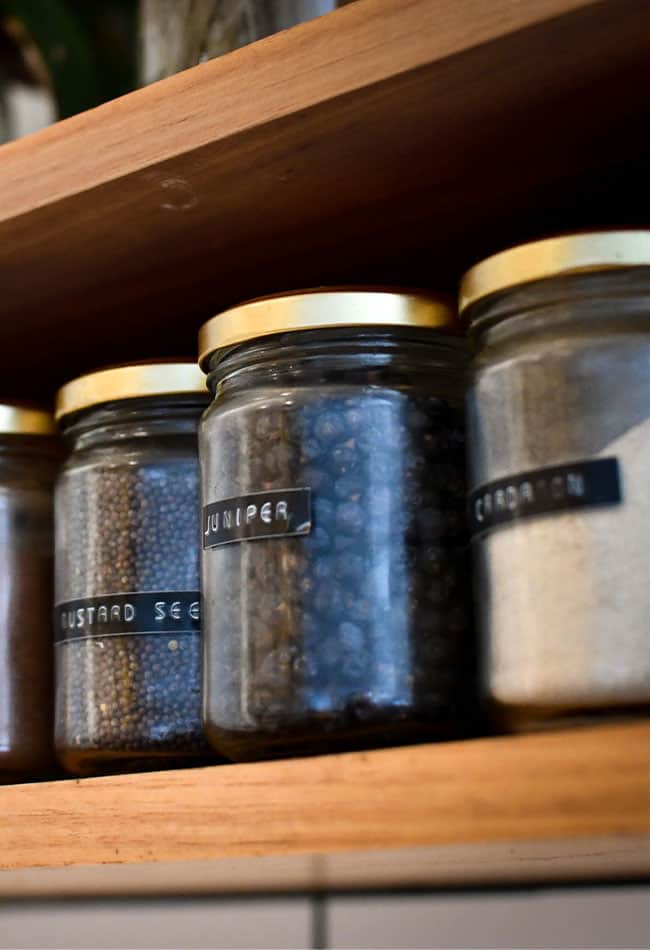 jars filled with spices on wooden shelf for pantry