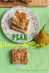 Pear Cheesecake Bars stacked on a plate next to another bar and a whole pear