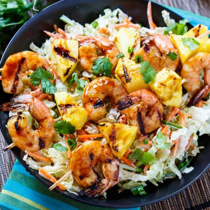 Grilled teriyaki shrimp and pineapple kebabs over asian slaw on a plate