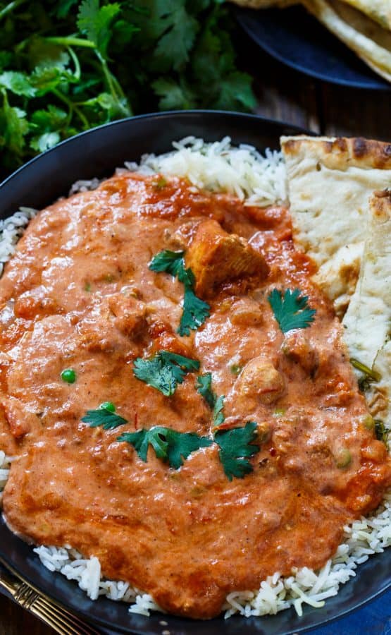 A plate of Chicken Tikka Masala over rice with pita bread